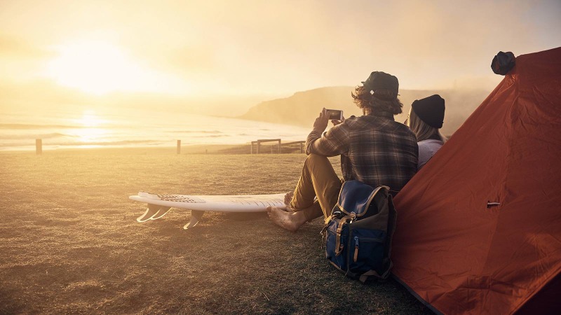 two people sitting on a beach and watching at a sunset